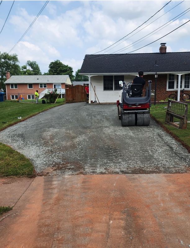 Cracked concrete driveway stripped to a compacted stone base before paving